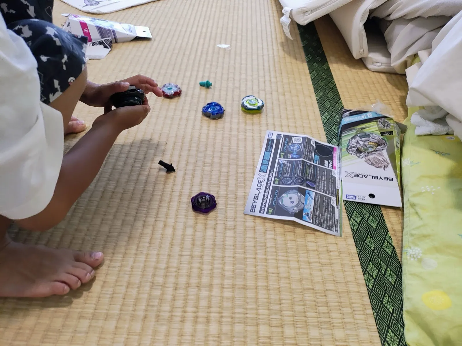 畳で取説を見ながらベイを組む子ども